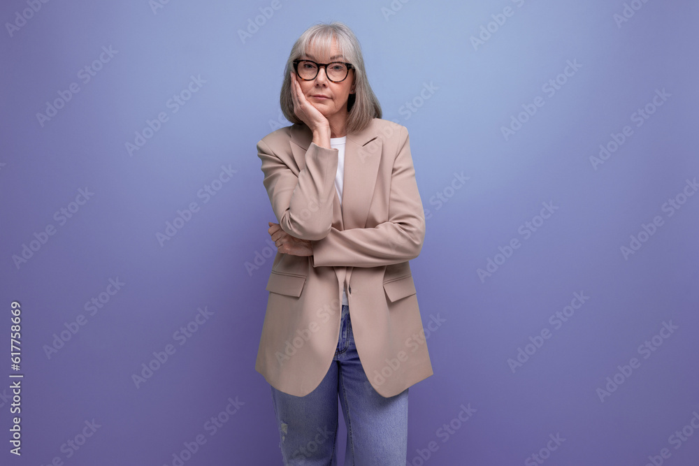 60s mature woman in business attire stands thoughtfully on a studio background with copy space 60s mature woman in business attire stands thoughtfully on a studio background with copy space