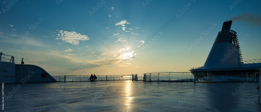 Panoramic view of a ship's deck at sunset with a lone couple
