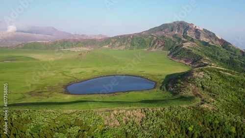 Mt Aso, Japan: Aerial drone footage of the Mt Aso volcano with the Eboshi and smoking Nakadake crater in the background in springtime near Kumamoto in Kyushu in Japan. Shot with a rotation motion. 
