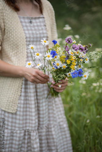 Photo of wildflowers in the hands of a girl.