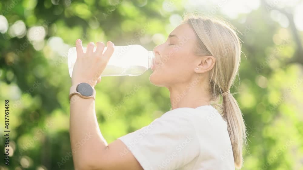 Portrait of pretty mature blond woman drinking fresh water from sport bottle during workout pause after fitness outdoors Pretty female keep health balance hydration during workout at park alone Portrait of pretty mature blond woman drinking fresh water from sport bottle during workout pause after fitness outdoors Pretty female keep health balance hydration during workout at park alone