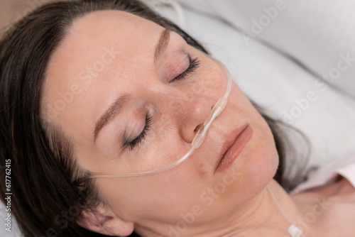 Portrait of a woman in a hospital bed with an oxygen mask. Unhealthy woman suffer from serious viral illness.