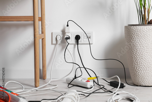 Schilderij op canvas Different electrical plugs in socket and power strip on floor indoors