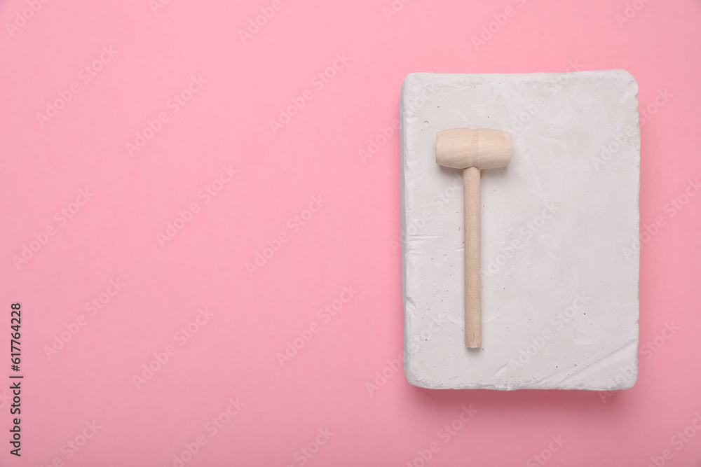 Educational toy for motor skills development. Excavation kit (plaster and wooden mallet) on pink background, top view with space for text Educational toy for motor skills development. Excavation kit (plaster and wooden mallet) on pink background, top view with space for text