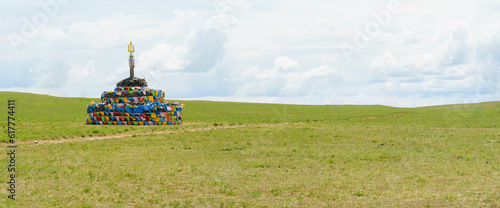 ovoo on the meadow. Mongolian meadow. panoramic view of the Mongolian grassland. stone mound prayer stone with colorful prayer flags. photo