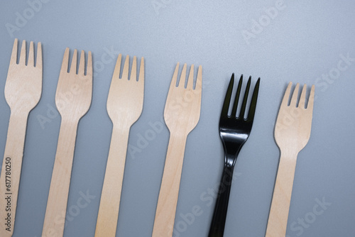 Plastic and wooden forks on a gray background. Save the ecology.