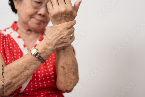 Elderly Asian woman patients suffer from numbing pain in hands from rheumatoid arthritis. Senior woman massage her hand with wrist pain. Concept of joint pain, rheumatoid arthritis, and hand problems. photo