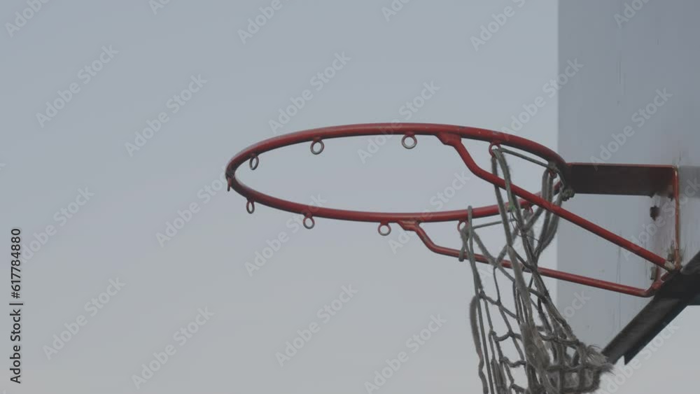 Basketball hoop with torn net shakes in wind against blue sky in clear weather. Entertainment for all ages. Game design with defect Basketball hoop with torn net shakes in wind against blue sky in clear weather. Entertainment for all ages. Game design with defect