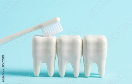 White brush cleans models of human teeth on blue background. Dental poster about the importance of brushing teeth.