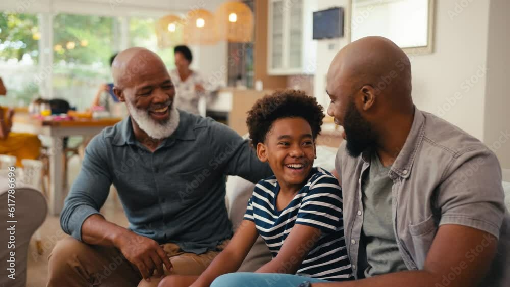 Laughing multi-generation male family hanging out sitting on sofa at home together chatting - shot in slow motion Laughing multi-generation male family hanging out sitting on sofa at home together chatting - shot in slow motion