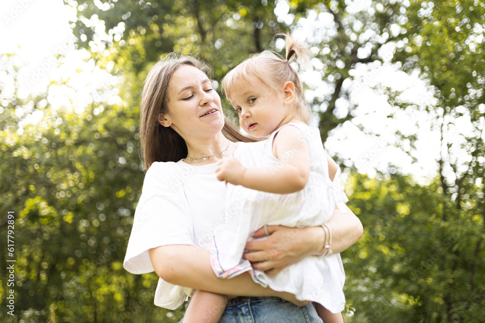A mother spends time with her two-year-old daughter. Mother and daughter are walking in the garden, hugging and having fun. Mother and her daughter. Maternal love and attachment. Tenderness. 