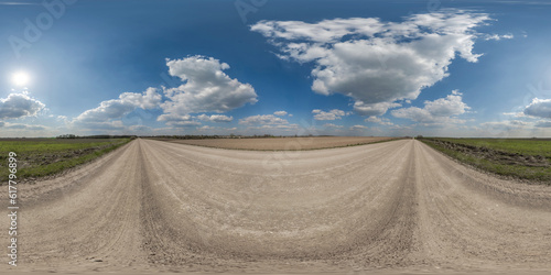 360 hdri panorama on gravel road with clouds and sun on blue sky in equirectangular spherical seamless projection, use as sky replacement in drone panoramas, game development sky dome or VR content