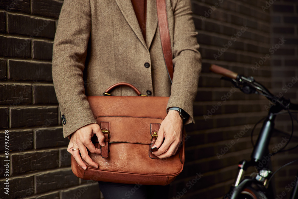 Fototapeta premium A busy businessman's hands, adjusting a business bag on the street.