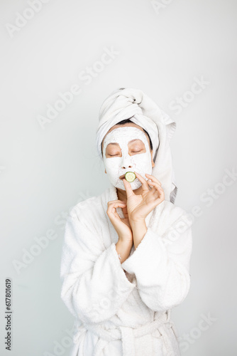 Cute Asian woman having fun with facial mask. Self-portrait of a charming model after a bath, wrapped in a towel taking a selfie on the front camera, applying using a face mask to her dry skin.
