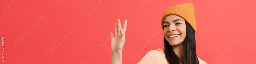 Young excited girl wearing hat waving and holding cellphone Young excited girl wearing hat waving and holding cellphone