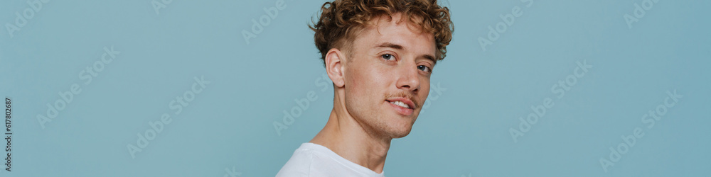 Obraz premium Young handsome curly man holding phone and looking at camera