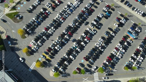 An aerial top overhead view of parking with many places near the supermarket. Cars moving around busy parking lot near shopping center. Drone footage of huge parking in Canada