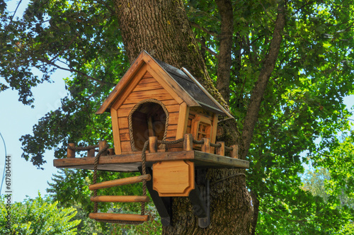 Beautiful wooden bird feeder in a rustic style with a ladder on a tree