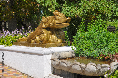 Old beautiful goldfish fountain in the city park on a sunny day