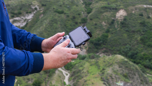 Hands of a young man with a drone remote controller in mountains, selective focus