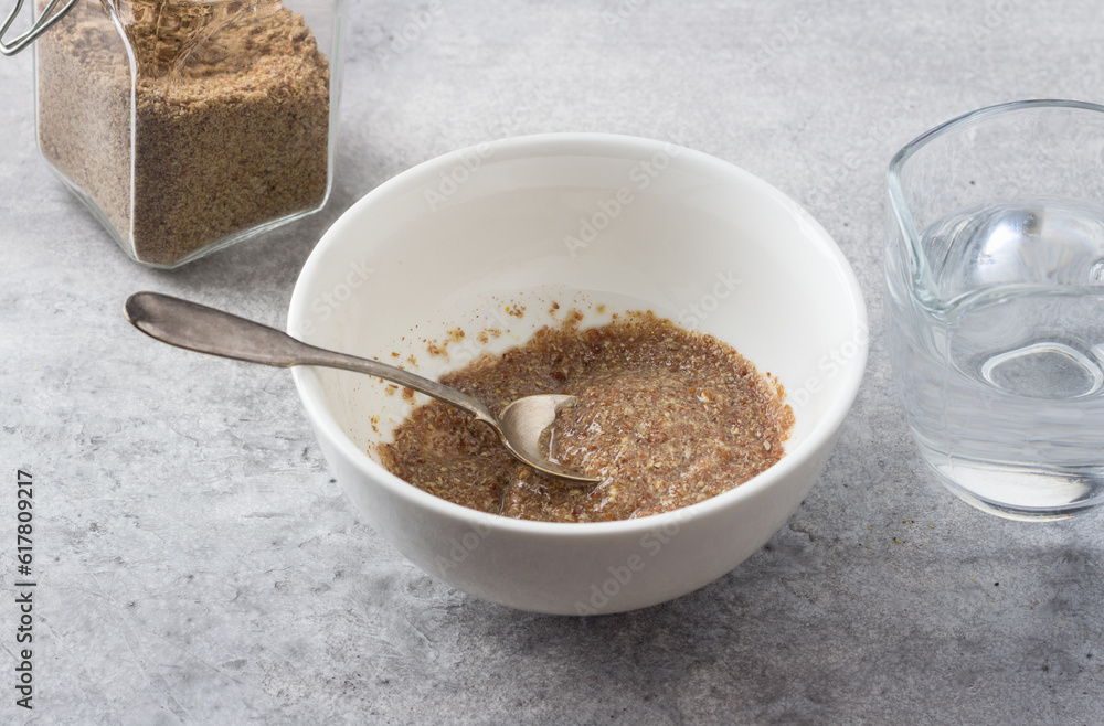 A bowl with ground flax and water, a jar of ground flax and a jug of water on a gray textured background. Cooking a vegan flax egg A bowl with ground flax and water, a jar of ground flax and a jug of water on a gray textured background. Cooking a vegan flax egg