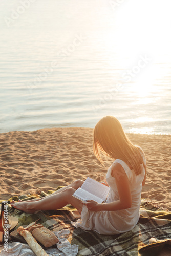 Obraz na płótnie Young woman reading a book at the beach. Back view w salonie