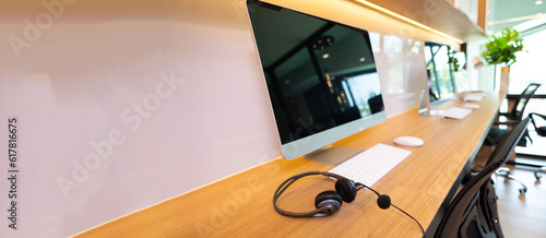 headset on desk with computer desktop at customer service and marketing support workplace. Office supplies of customer service. Communication support, call center and helpline concept.