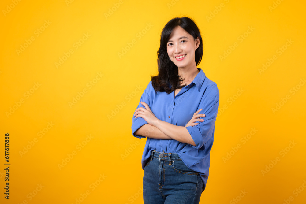 Radiate confidence with captivating portrait. A young Asian woman wearing a blue shirt showcases happy smile while crossing her arms. Perfect for conveying a sense of self-assurance and determination. Radiate confidence with captivating portrait. A young Asian woman wearing a blue shirt showcases happy smile while crossing her arms. Perfect for conveying a sense of self-assurance and determination.