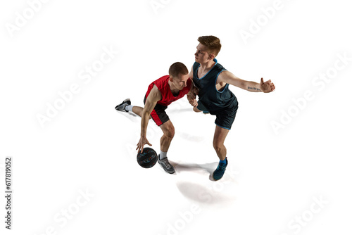 Two man, professional basketball players in motion, playing with ball, training isolated against white background. Concept of sport, action and motion, health, game, hobby, sportswear, ad