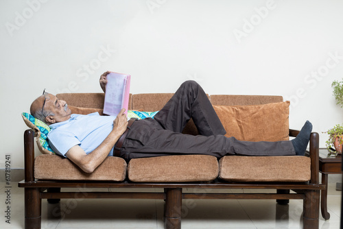 Billede på lærred Indian senior man Reading book while lay down at sofa at living room,Retirement