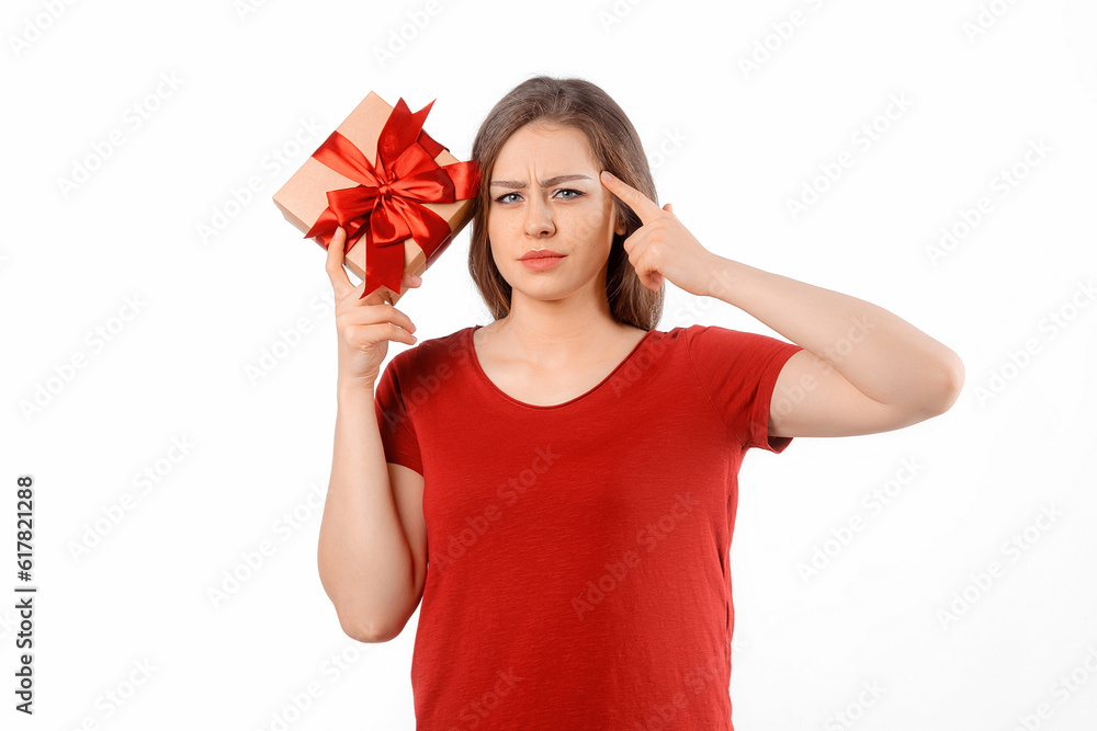 Portrait of a charming curious girl holding gift box at her ear and posing over white background. International Women's Day, New Year, Christmas, Birthday and Valentine's Day concept celebration Portrait of a charming curious girl holding gift box at her ear and posing over white background. International Women's Day, New Year, Christmas, Birthday and Valentine's Day concept celebration