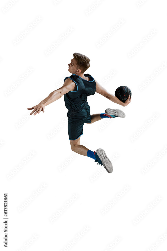 Full-length image of young man, basketball player in jump with ball isolated against white background. Winning goal. Concept of sport, action and motion, health, game, hobby, sportswear, ad