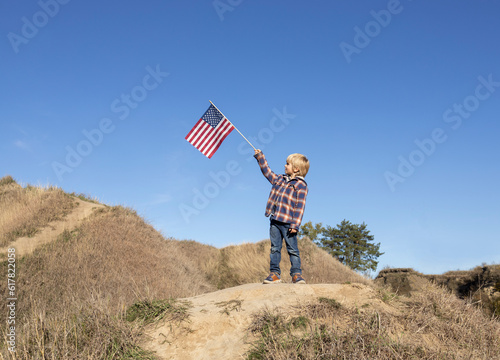 Wallpaper Mural Patriotic boy 6 years old proudly raised the American flag against the blue sky. Celebration of Independence Day of the United States of America. happiness, success, freedom, national symbol Torontodigital.ca