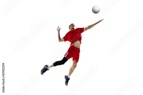 Young man, professional athlete in red uniform in motion, hitting ball in jump, playing volleyball against white studio background. Concept of sport, active lifestyle, health, dynamics, game, ad