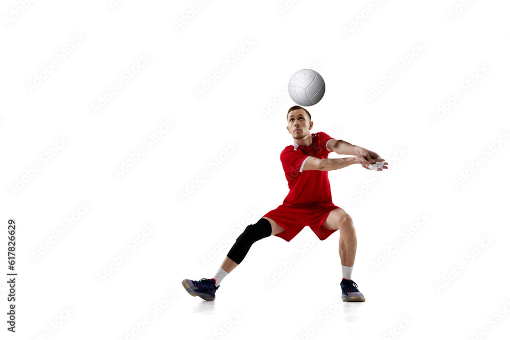 Serving ball. Young concentrated man, professional volleyball player in red uniform in motion against white studio background. Concept of sport, active lifestyle, health, dynamics, game, ad