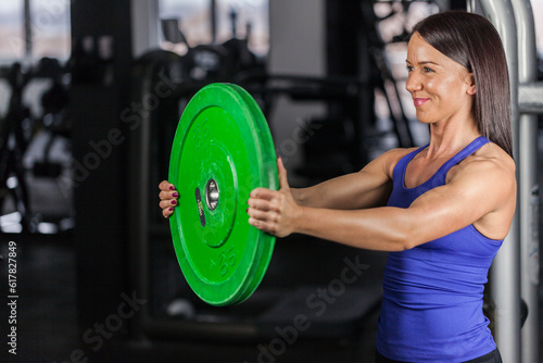 young attractive beautiful girl with a smile, workout with one big green weight. copy space