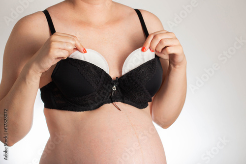 A girl in a black bra puts pads from the flow of milk in her bra. Soft, hypoallergenic breast pads. photo