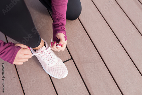 Female hands tying shoelace on running shoes before practice. Runner getting ready for training. Sport active lifestyle concept.