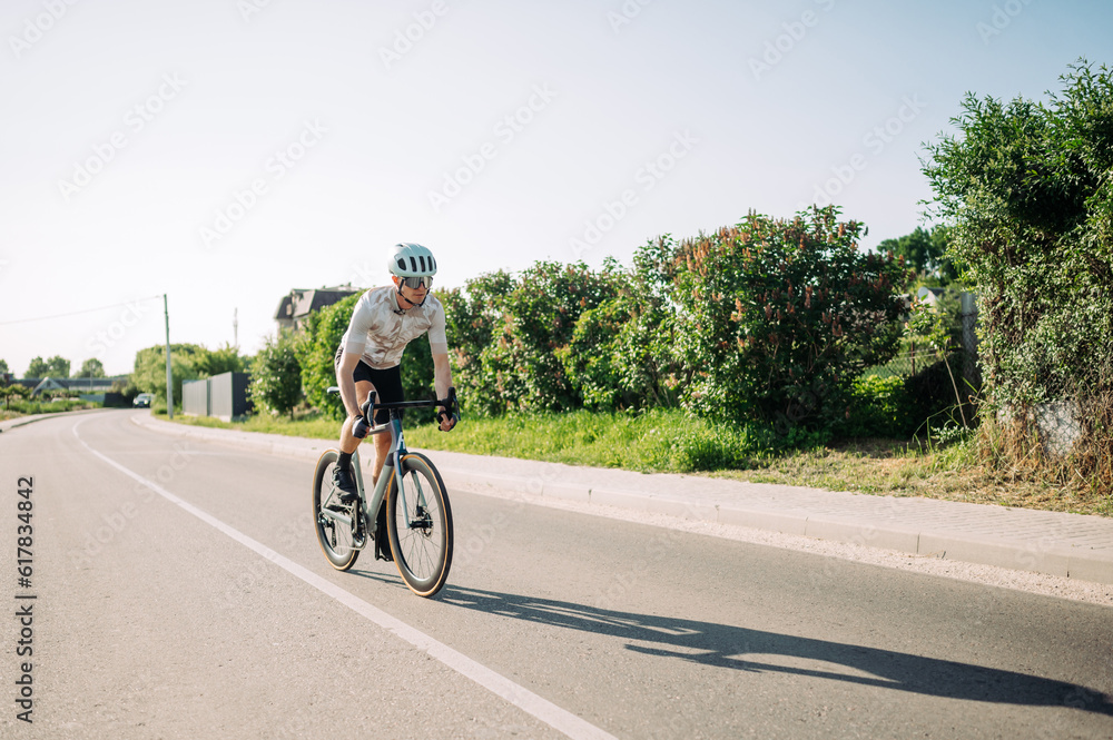 Obraz premium Cyclist athlete trains outside the city on a bicycle and rides fast on the road. Recreation.