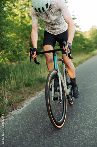 Close up photo. A man rides a road bike on a country road. © bodnarphoto