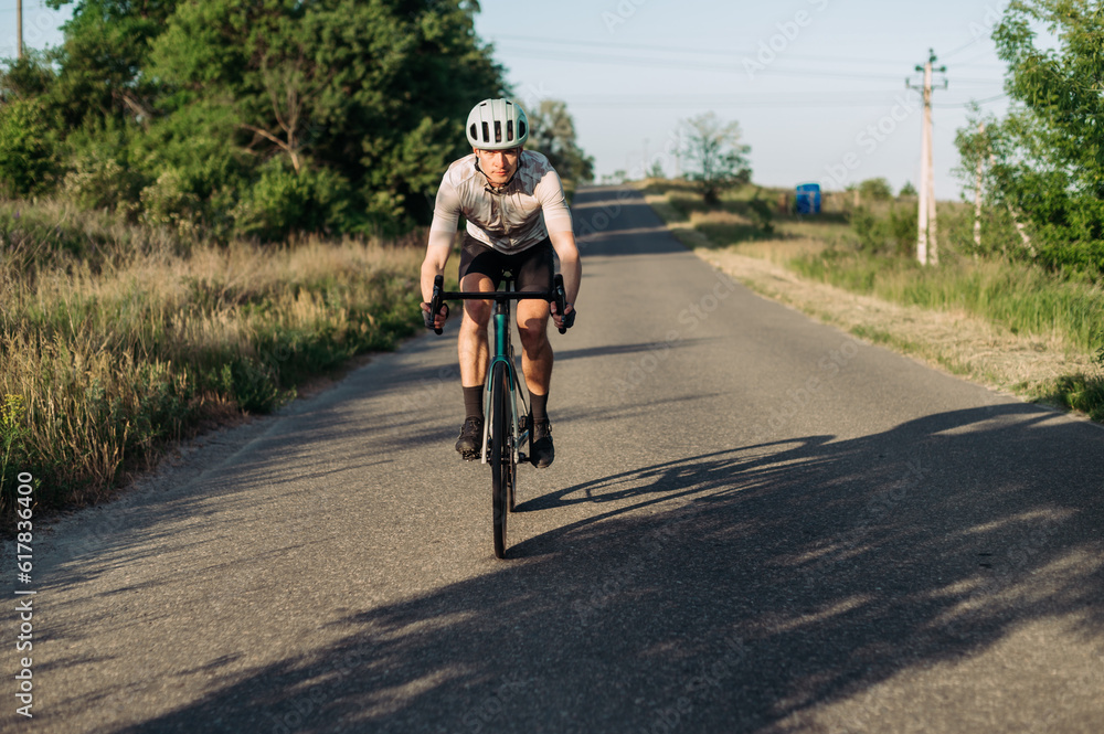 Sporty young man cyclist in gear goes down a hill on a road bike outside the city. Bicycle training.