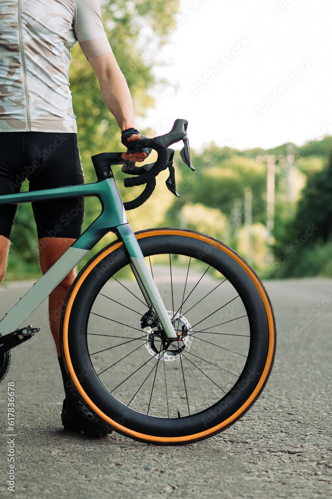 Close-up of the front of a bicycle and a cyclist on a country road. Cycling concept Close-up of the front of a bicycle and a cyclist on a country road. Cycling concept