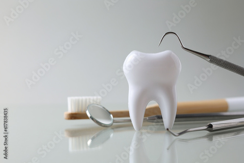 Dentistry concept. Model of a tooth and dental instruments on a light background with space for text. 