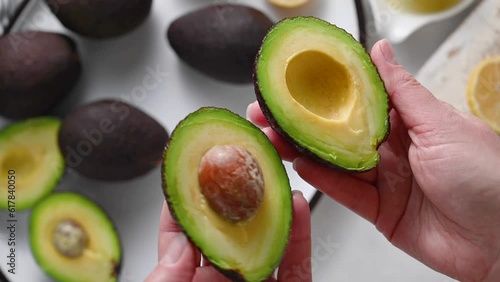 Fresh avocado. Woman holding half of fresh ripe avocado, top view