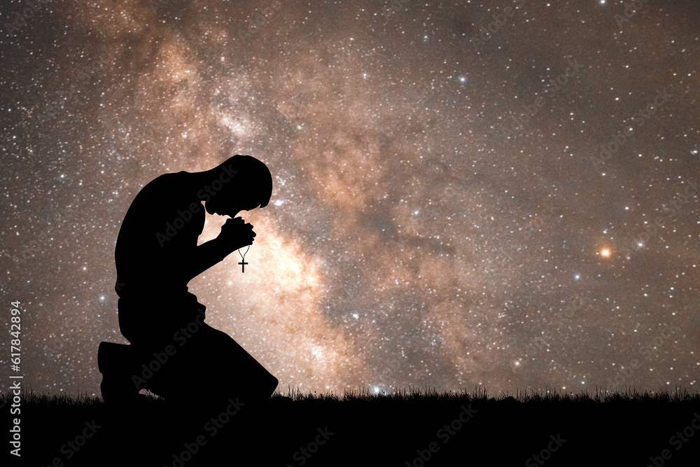 Desperate man praying to god At night, the Milky Way and the stars are beautiful.