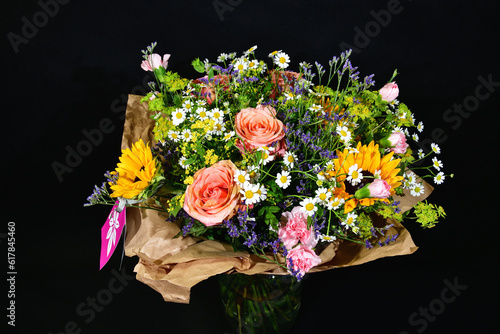 Beautiful colorful bouquet with roses and sunflowers among meadow flowers. Focused on the center of the image.