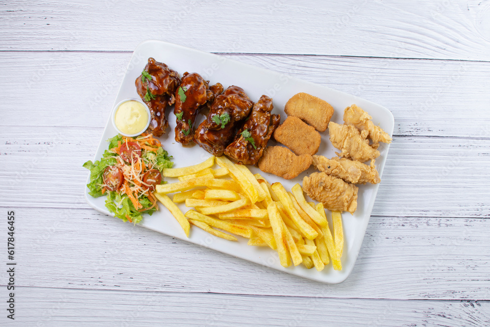Chicken mix, wings in bbq sauce, nuggets and chicken pieces, accompanied by French fries, salad and mayonnaise
