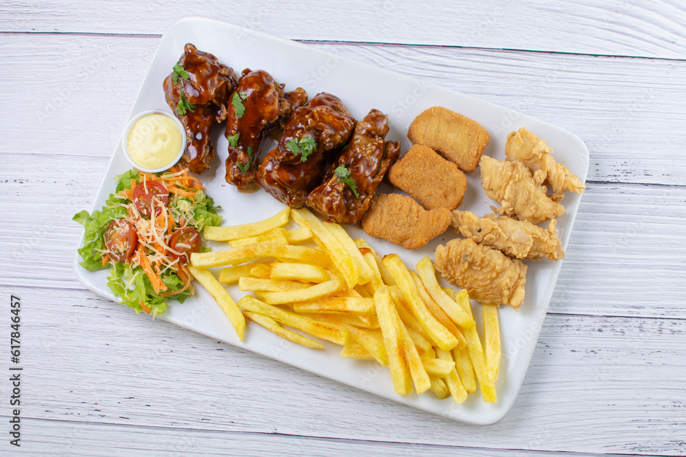 Chicken mix, wings in bbq sauce, nuggets and chicken pieces, accompanied by French fries, salad and mayonnaise