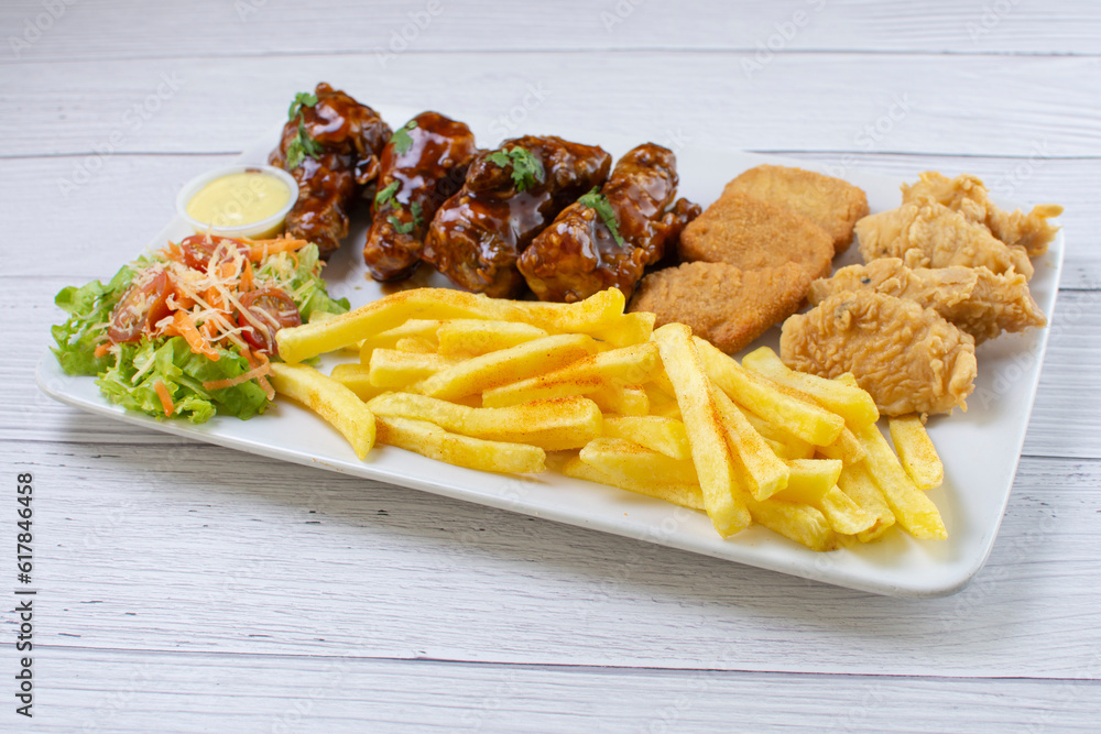 Chicken mix, wings in bbq sauce, nuggets and chicken pieces, accompanied by French fries, salad and mayonnaise
