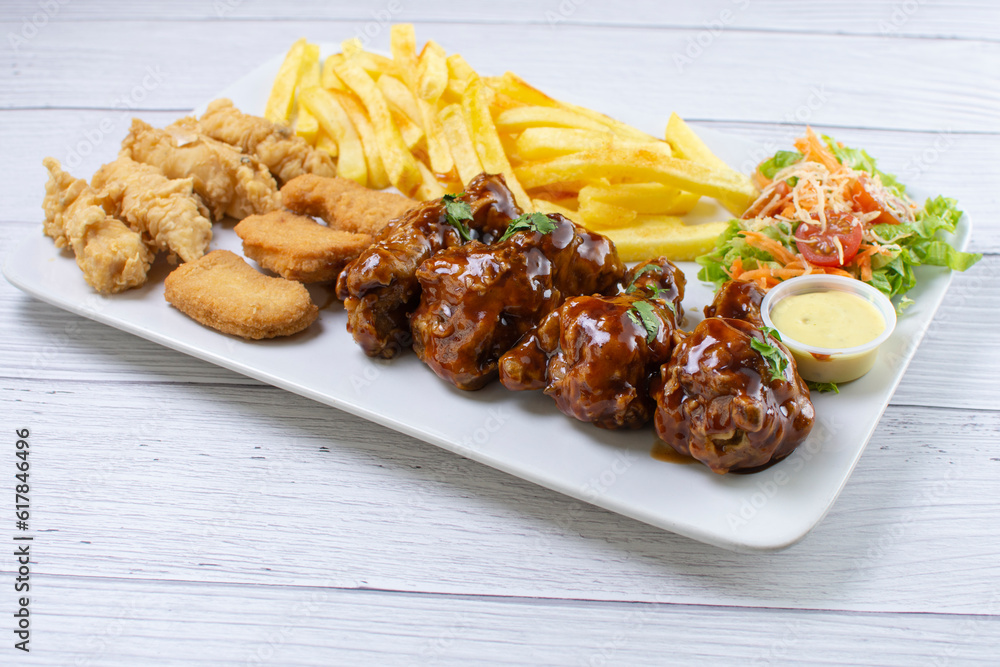 Chicken mix, wings in bbq sauce, nuggets and chicken pieces, accompanied by French fries, salad and mayonnaise